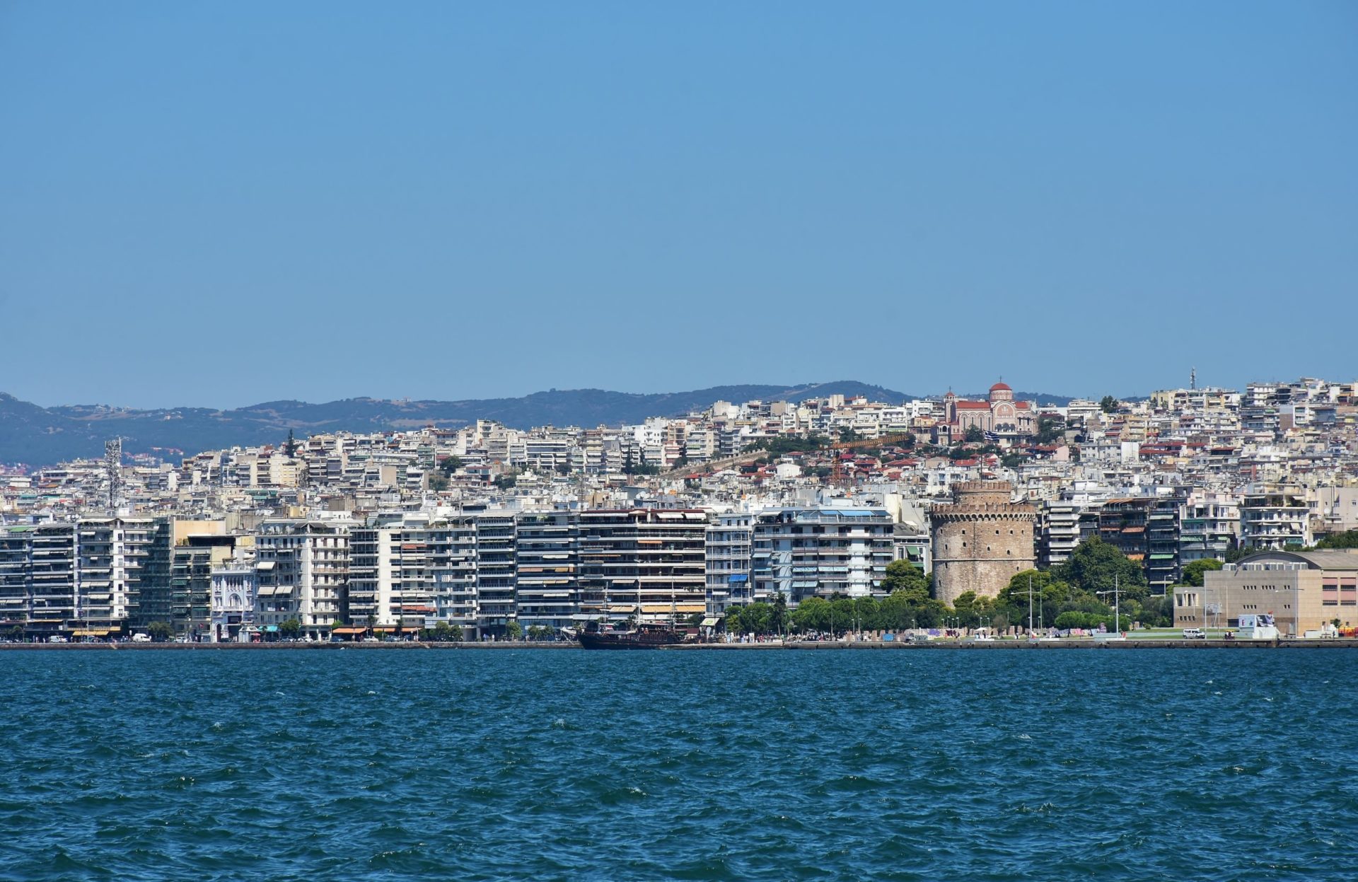 Wassertemperatur Thessaloniki: Blick über den Thermaischen Golf auf das Ufer von Thessaloniki mit dem von Bäumen umgebenen Weißen Turm